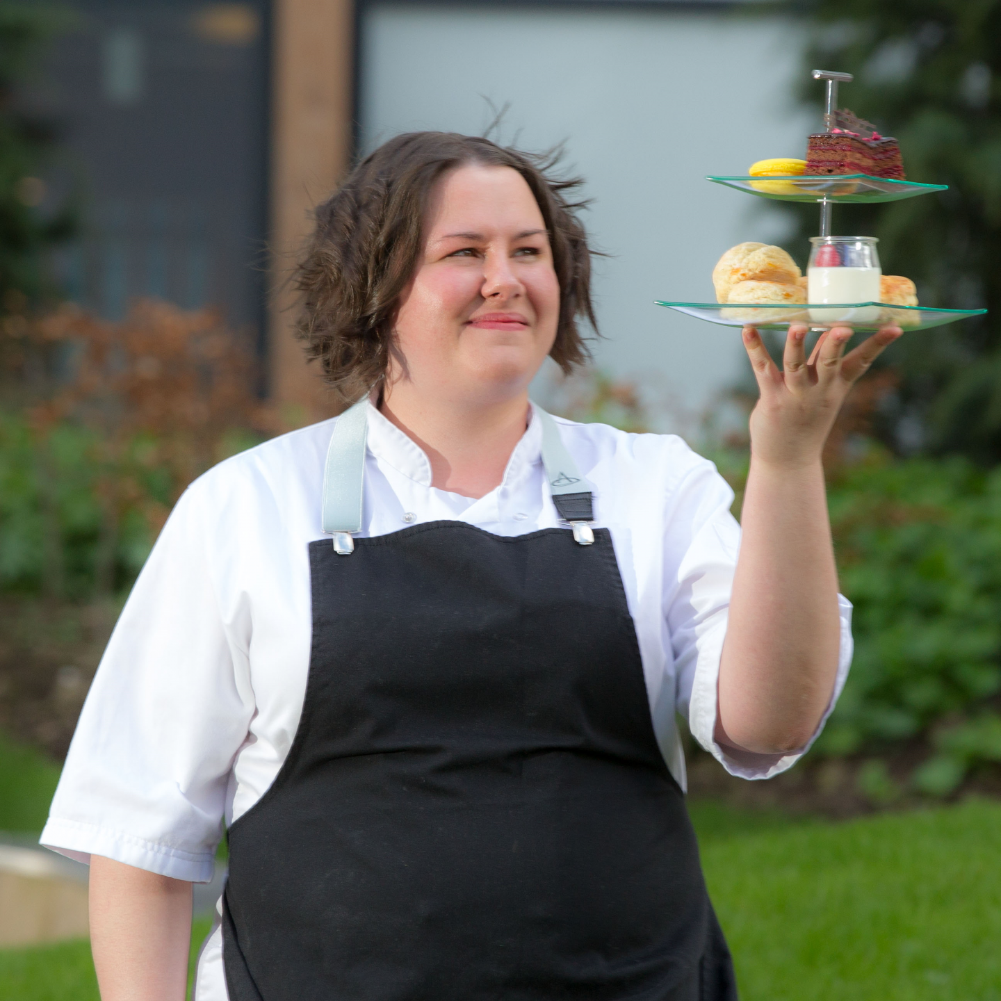 An image of Helen Vass, a GCU alumna and a pastry chef, smiling while holding a cake platter.