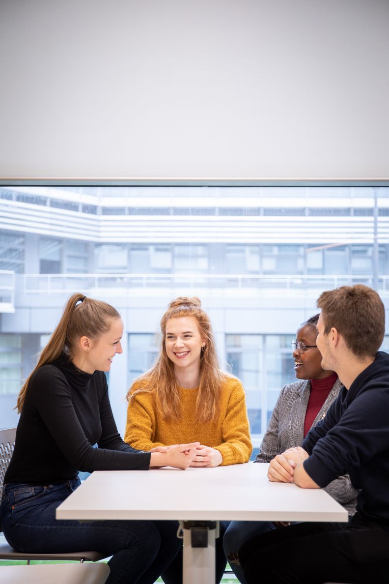 Undergraduate students sitting around a table talking.