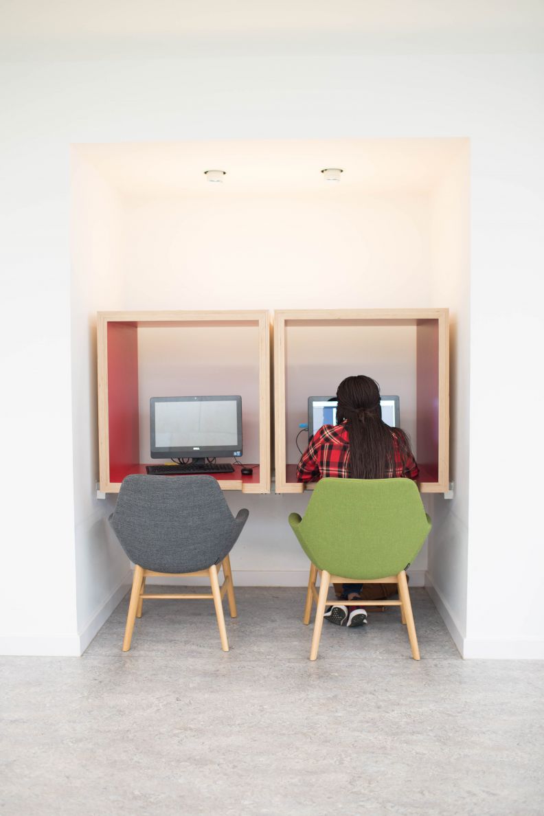 Students in check shirt using computer in a study pod at Glasgow Caledonian University