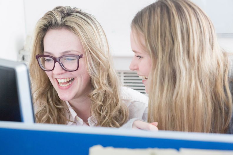 Two female students laughing while studying at Glasgow Caledonian University